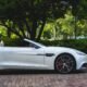 white Aston Martin convertible parked near trees