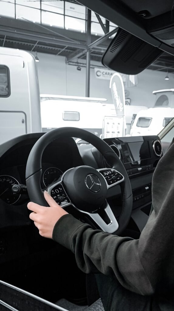 a person sitting in a car with a steering wheel