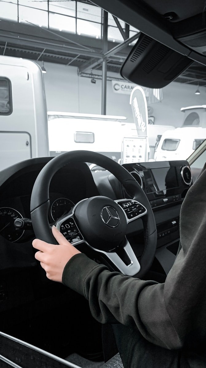 a person sitting in a car with a steering wheel