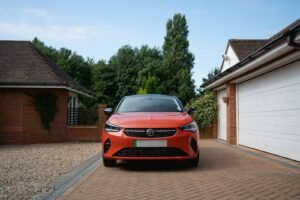 Orange car parked in driveway between garages.