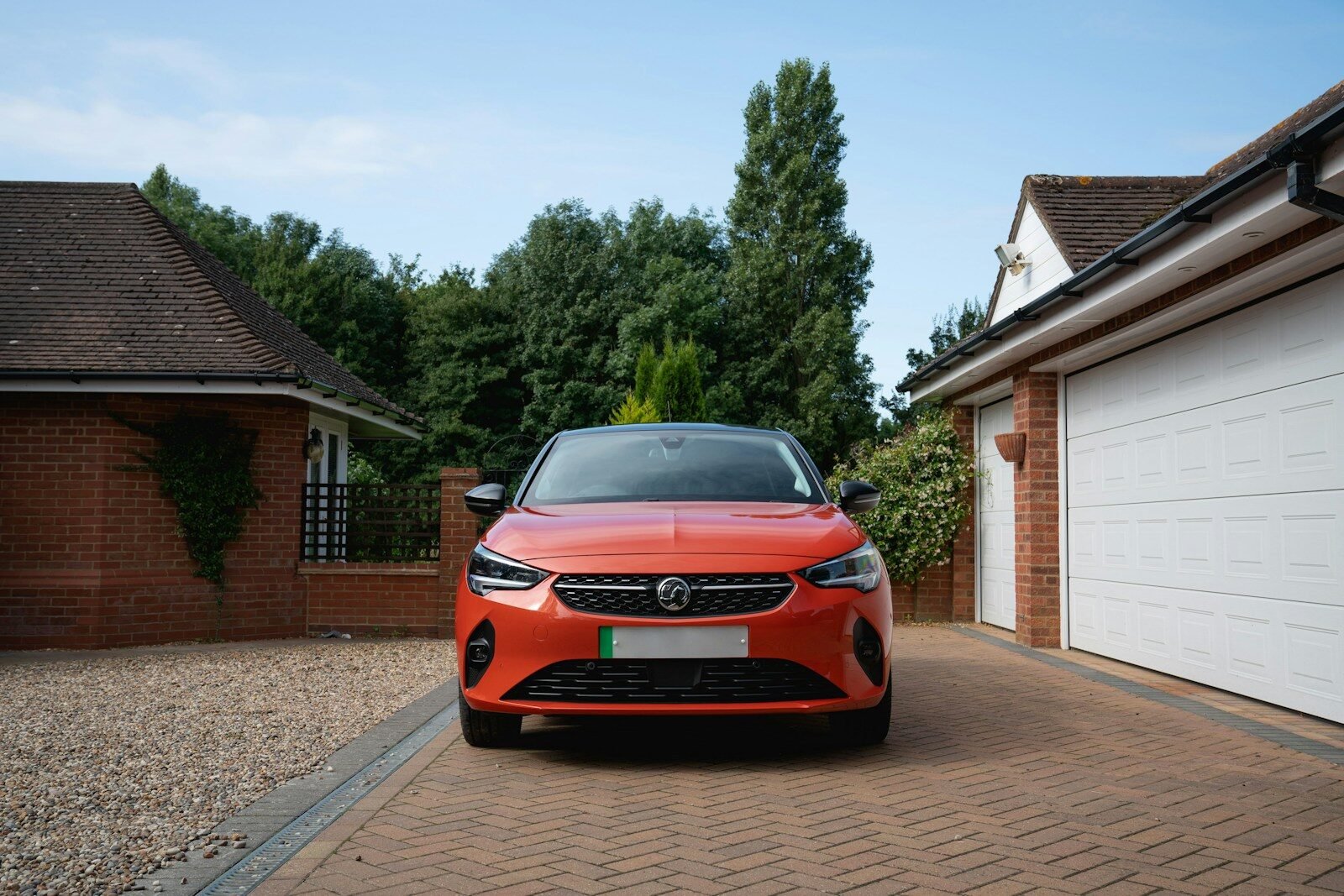 Orange car parked in driveway between garages.