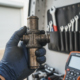 Gloved hand holding a heavily carboned EGR valve removed from a diesel engine