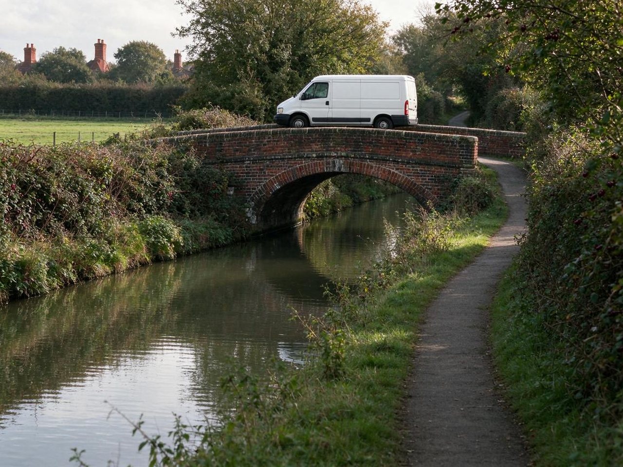 White van crossing a red-brick canal bridge in the countryside near Alsager