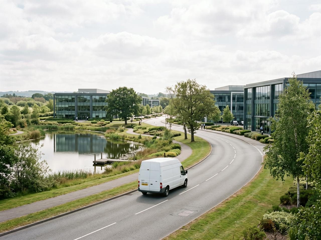 White van on a curving road through a business park with a lake near Crewe