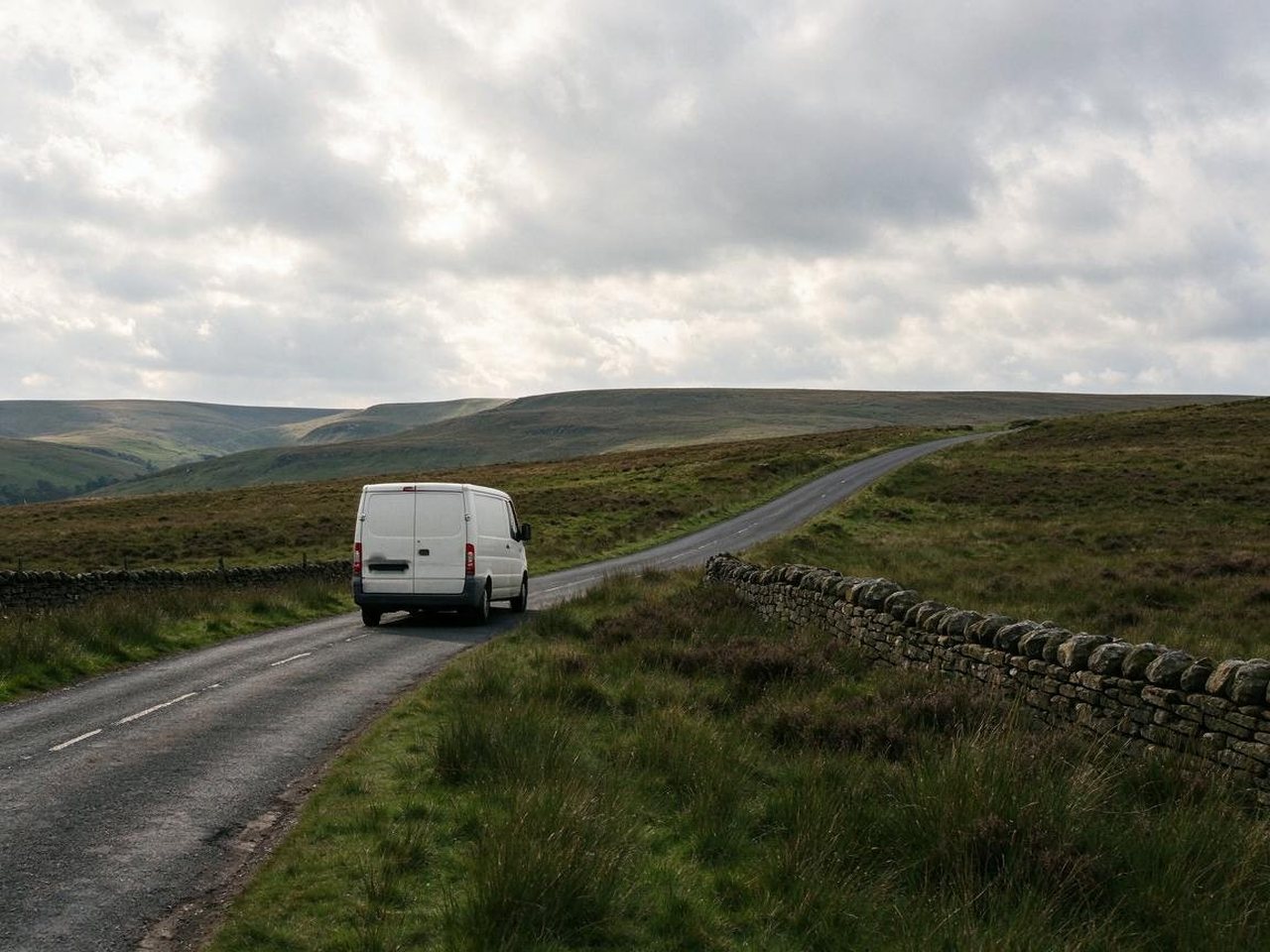 White van on a moorland road with dry-stone walls in the hills east of Macclesfield