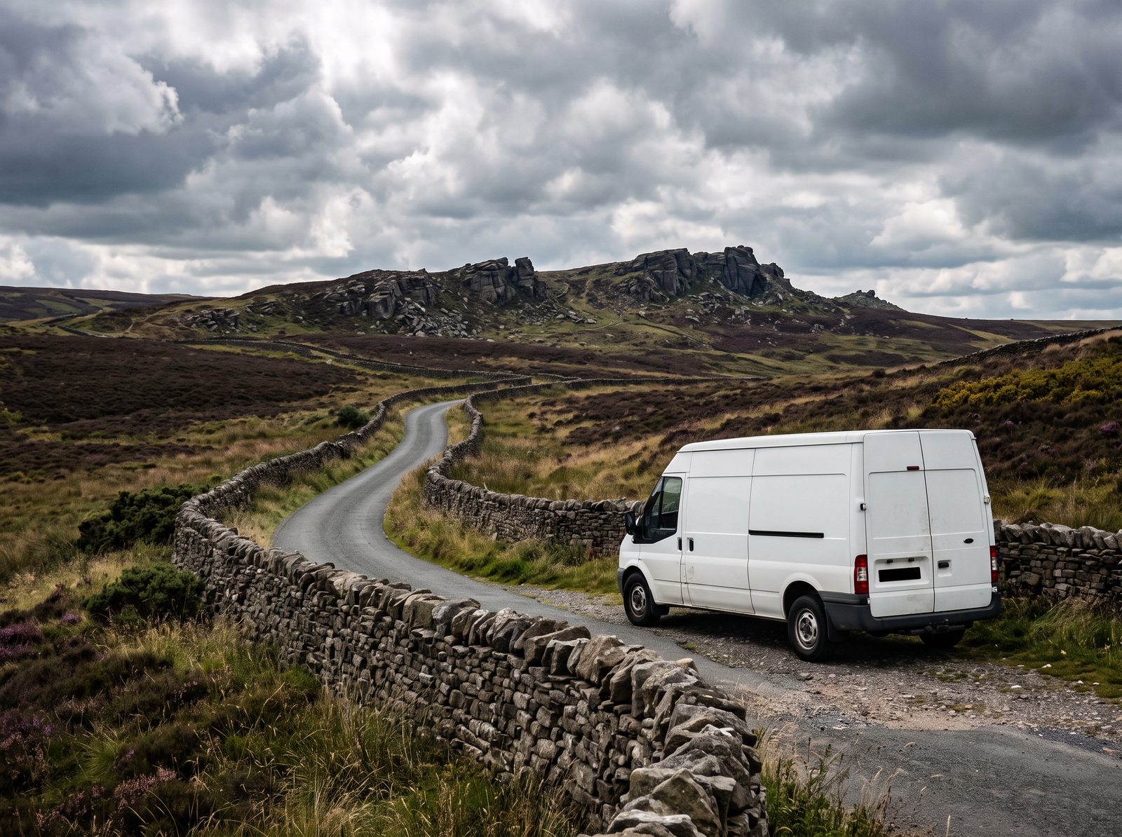 White van parked by a dry stone wall on a moorland road below a gritstone ridge in the Staffordshire Moorlands
