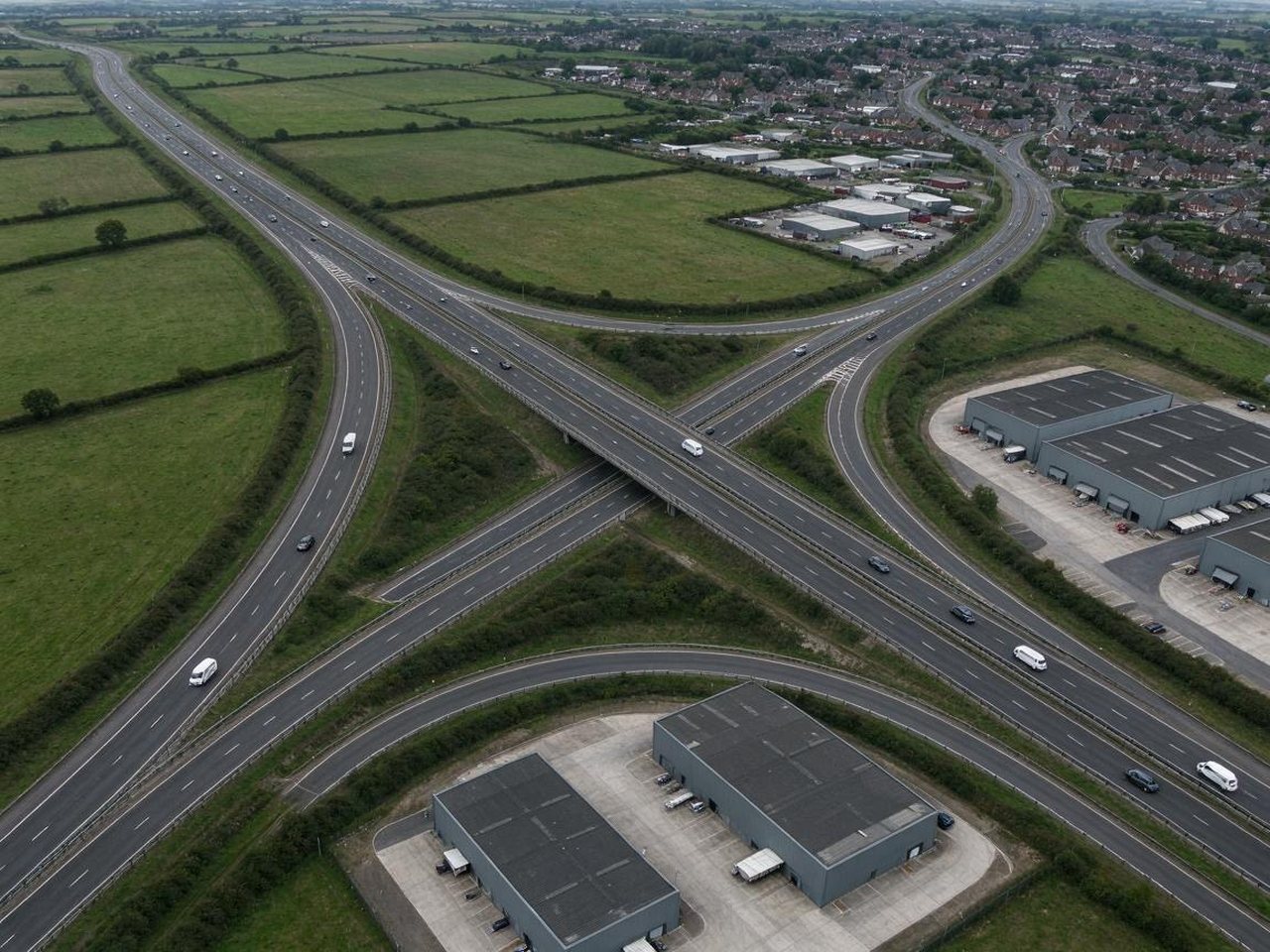 Aerial view of a dual carriageway and motorway junction beside warehouses on the edge of Tamworth